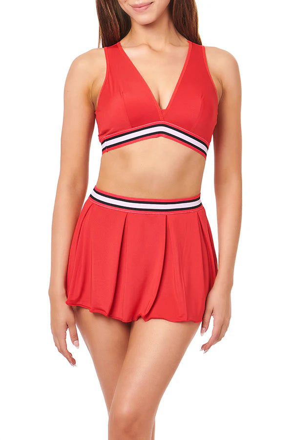 Red two-piece outfit with a sports bra and pleated skirt on a white background