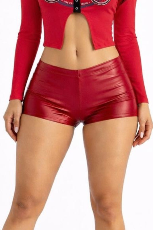 Person wearing a red long-sleeve top and red leather shorts on a white background