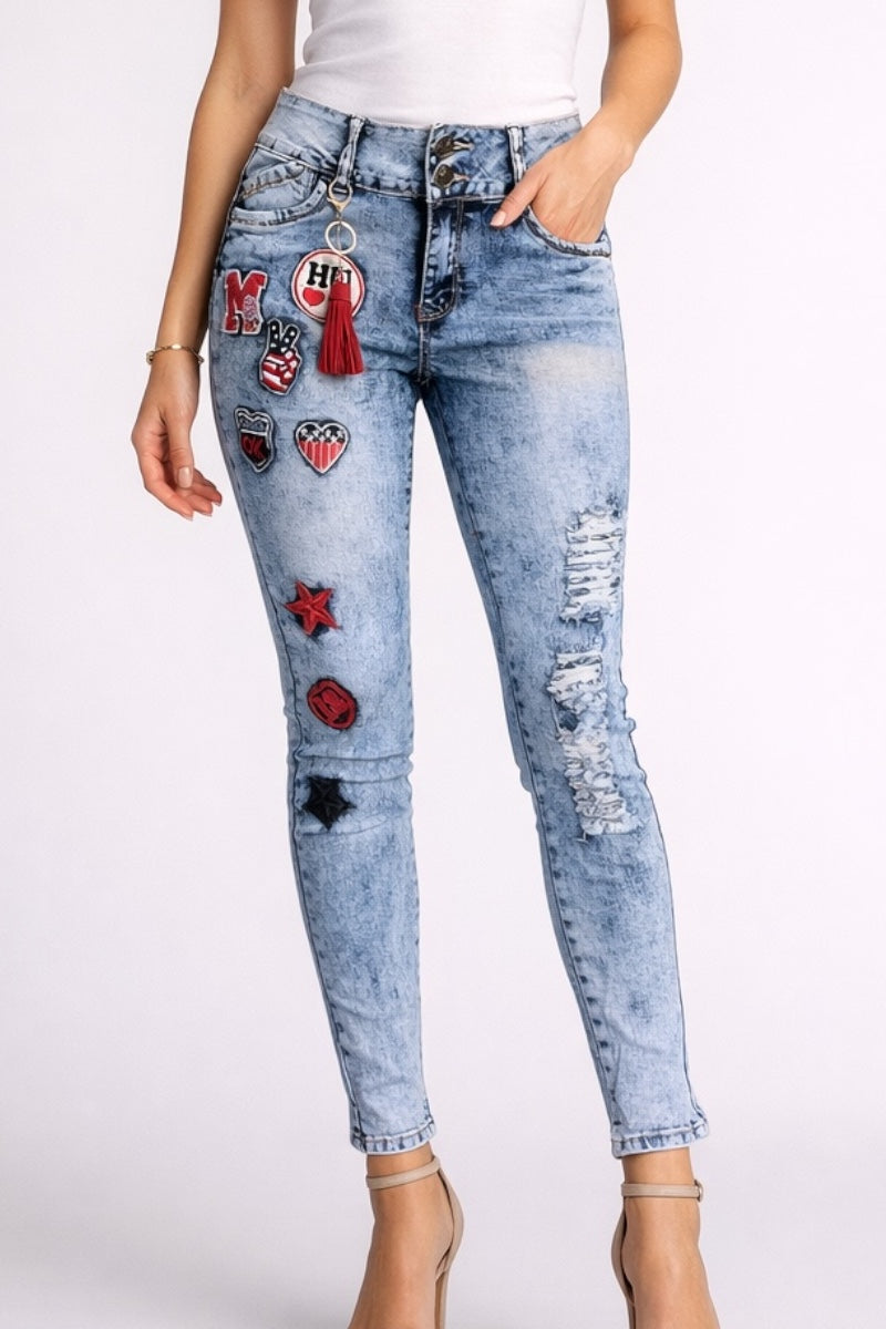 Light blue jeans with various patches worn by a person on a white background