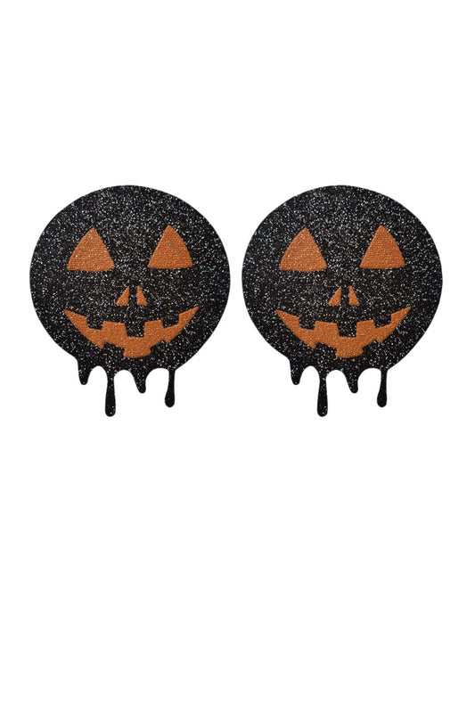 Two black glittery Halloween pasties with jack-o'-lantern faces on a white background.