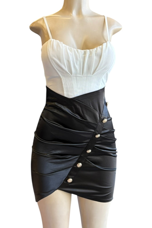 Mannequin wearing a white top and black skirt dress with button details on a white background