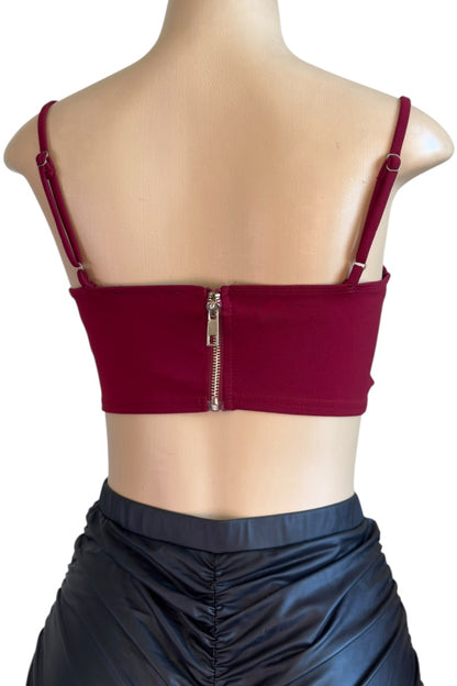 burgundy crop top with thin straps and zipper on a mannequin against a white background