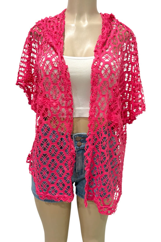 Mannequin wearing a bright pink crochet cardigan over a white top and denim shorts on a white background.