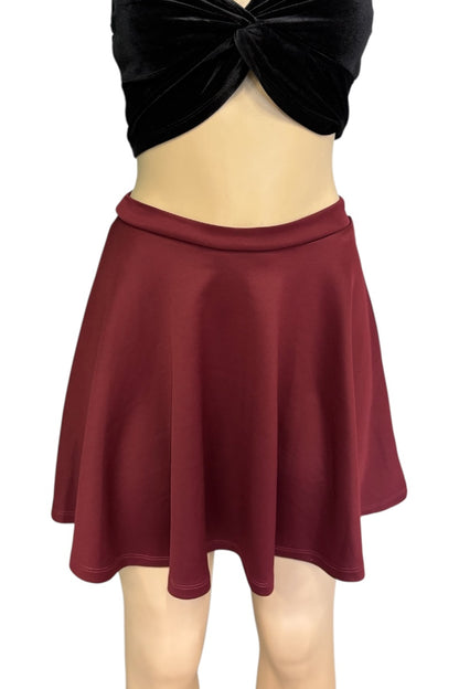 A dark red flared mini skirt shown on a mannequin torso, paired with a black velvet top against a plain white background.
