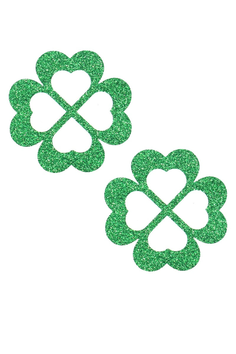 Two green glittery four-leaf clover pasties on a white background