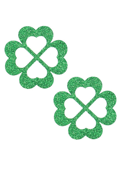 Two green glittery four-leaf clover pasties on a white background