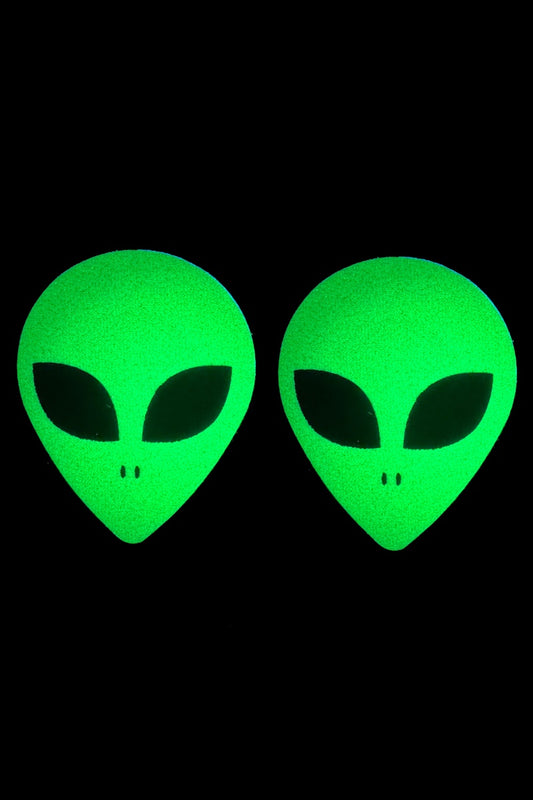 Two green alien head pasties on a black background