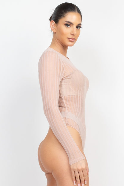 Woman wearing a sheer beige long-sleeve bodysuit on a white background