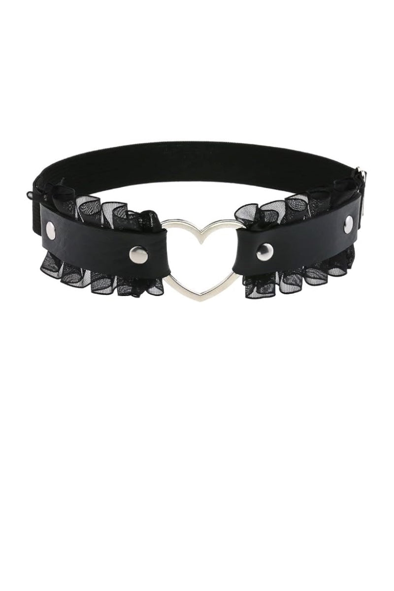 A black faux-leather leg garter featuring a central silver heart-shaped metal clasp and layered black sheer ruffled trim on both sides, displayed against a solid white background.