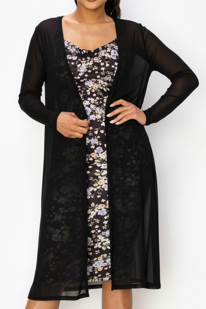 Woman wearing a black long-sleeve sheer cardigan over a floral dress against a white background