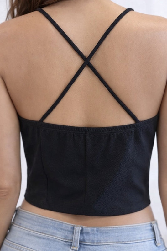 Black crop top with criss-cross back design on a plain background