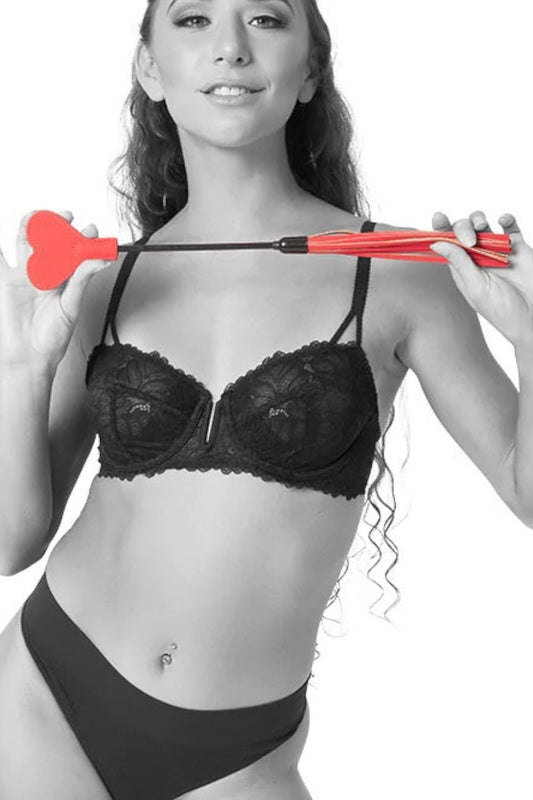 Woman in black lingerie holding a red dart with a white heart on a white background
