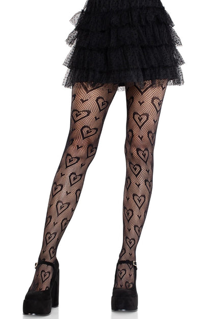 Black tights with a repeating heart pattern, worn by a model with a black ruffled mini skirt and black platform heels against a white background.
