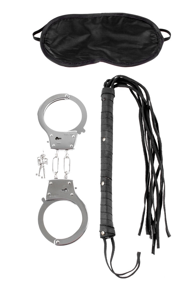 Set of handcuffs, black leather whip, and black satin eye mask on a white background