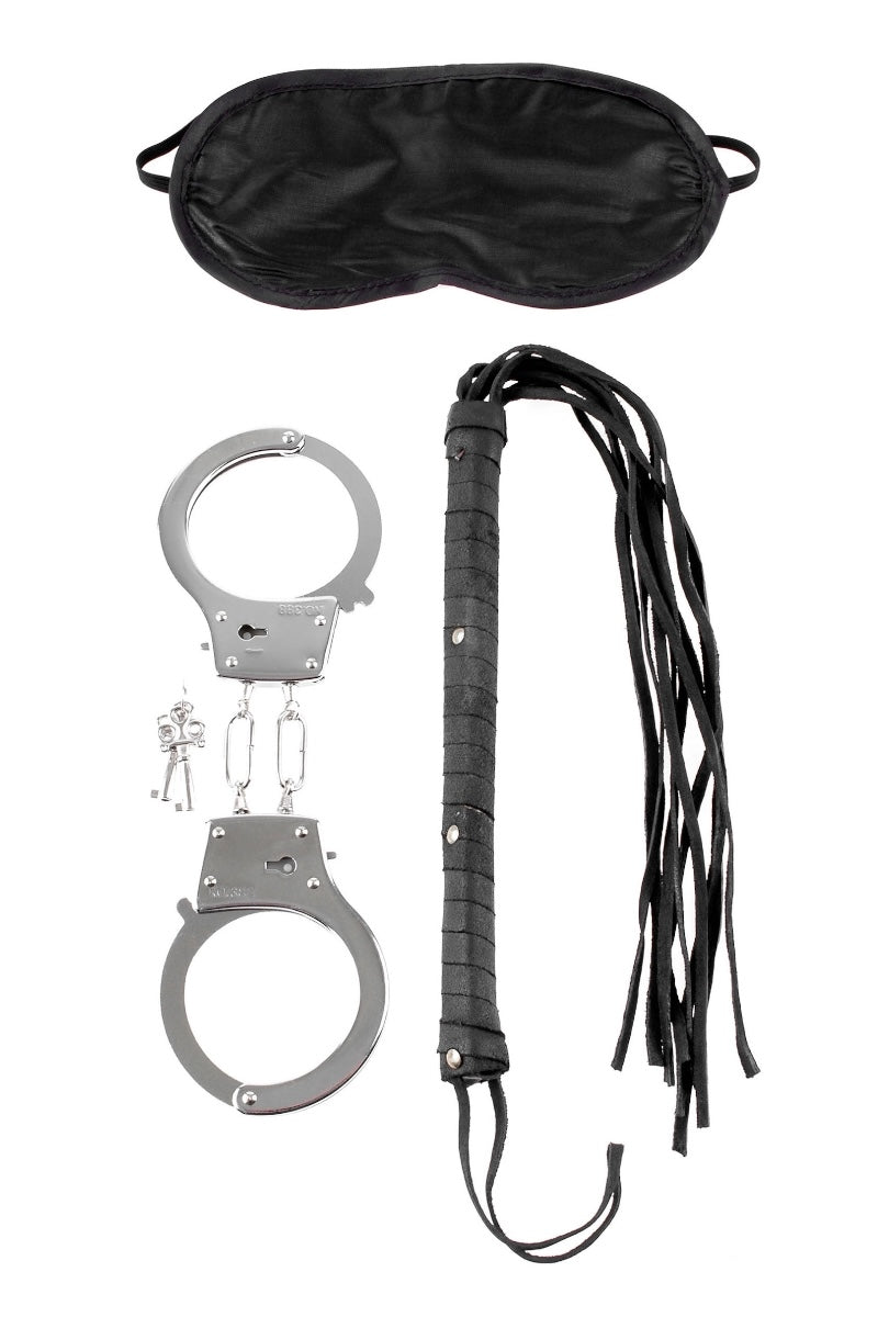 Set of black leather flogger, silver handcuffs, and black satin eye mask on a white background