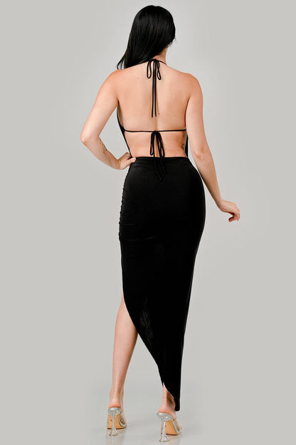 Woman wearing a black dress with a high slit on a gray background