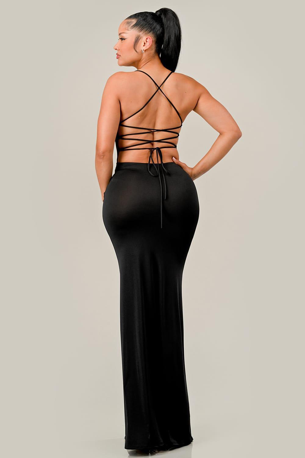 Woman wearing a black dress with strappy back design on a plain background