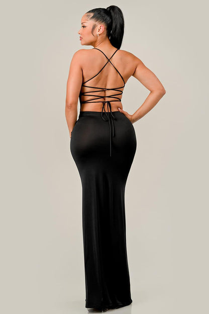 Woman wearing a black dress with strappy back design on a plain background