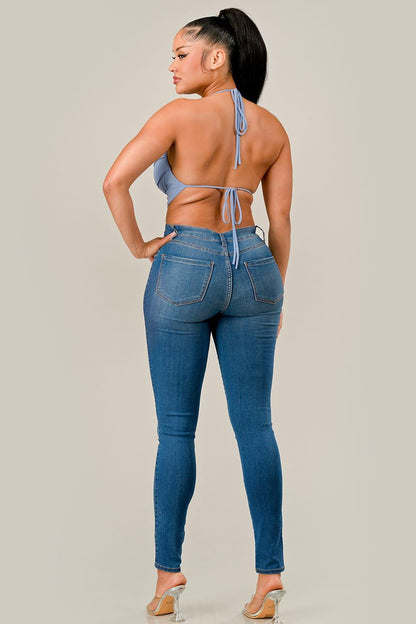 Woman wearing blue jeans and a light blue bikini top on a plain background