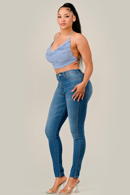 Woman wearing a light blue top and dark blue jeans on a plain background