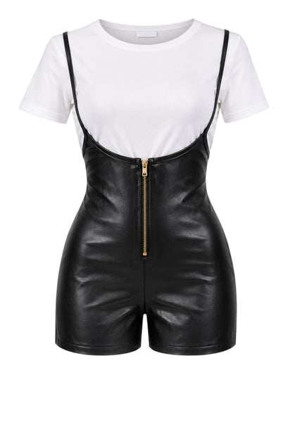 A black faux leather romper with thin shoulder straps, a gold front zipper, and a white short-sleeve crewneck bodysuit underneath, shown on a plain white background.