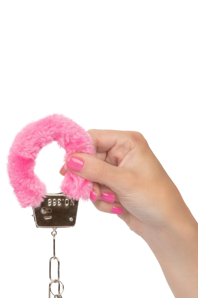 Hand holding a pink fluffy object with a metal clasp on a white background