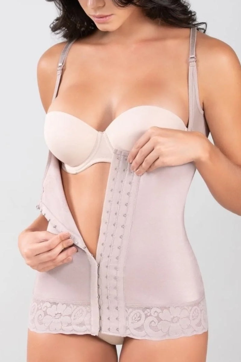 A woman wearing a light beige shapewear bodysuit with a built-in bra, shown from the chest down against a plain light gray background.