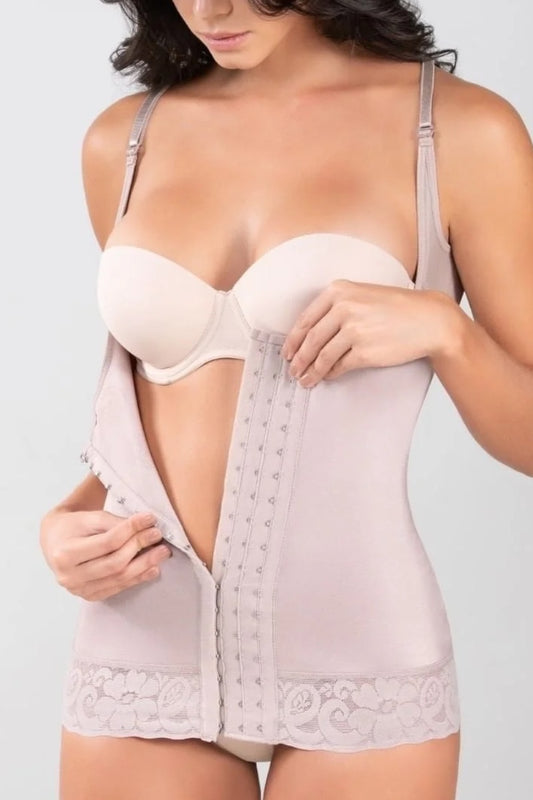 A woman wearing a light beige shapewear bodysuit with a built-in bra, shown from the chest down against a plain light gray background.