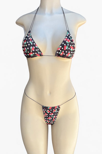 Bikini set with cherry pattern on a mannequin against a white background