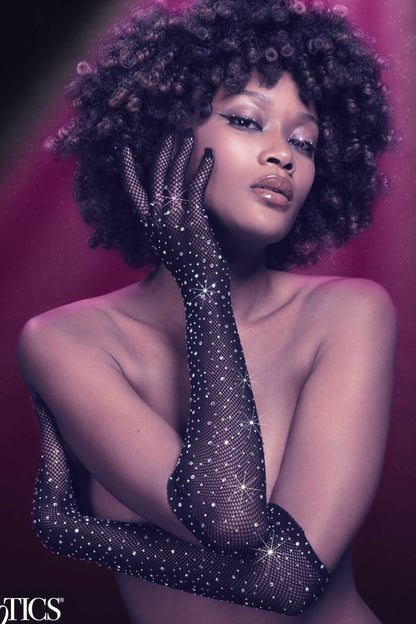 Woman wearing sparkling black fishnet gloves against a pink background