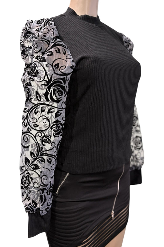 Black top with floral patterned sleeves on a mannequin against a white background