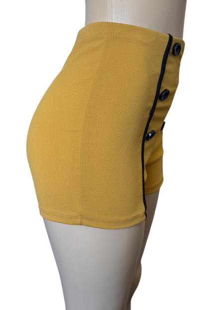 Mustard shorts with black buttons on a mannequin against a white background