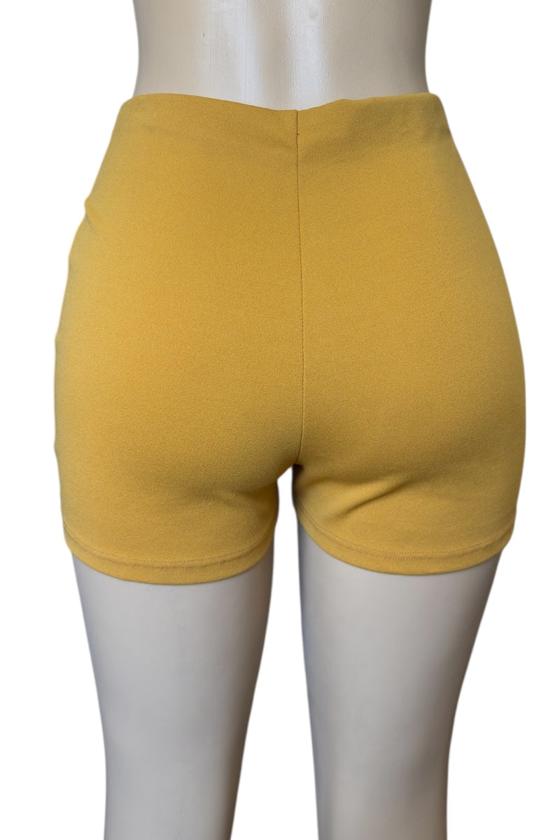 Mustard shorts on a mannequin against a white background