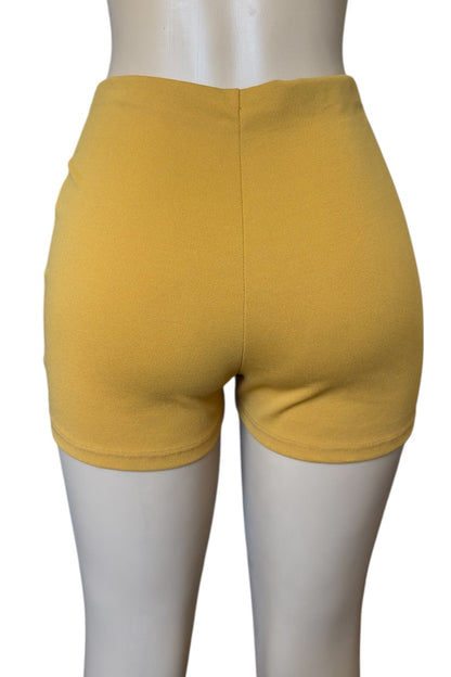 Mustard shorts on a mannequin against a white background
