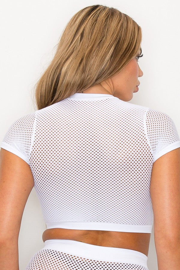 Woman wearing a white mesh top against a plain background