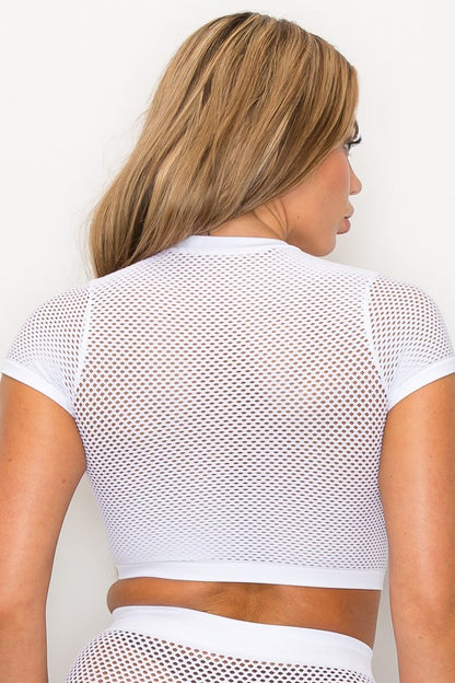 Woman wearing a white mesh top against a plain background