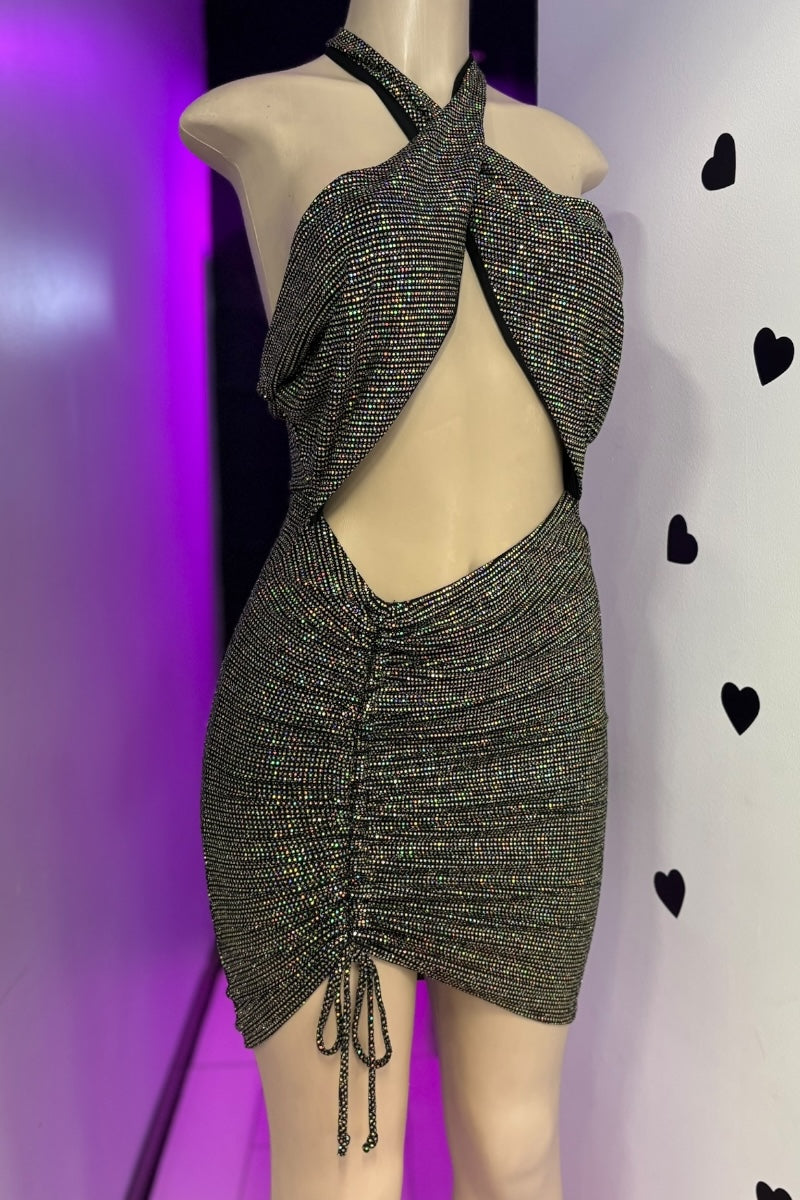 Mannequin wearing a sparkly black dress with a halter neck and open back against a purple and white background.
