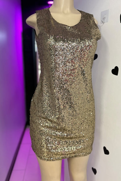 Gold sequin dress on a mannequin against a white wall with black heart shapes.