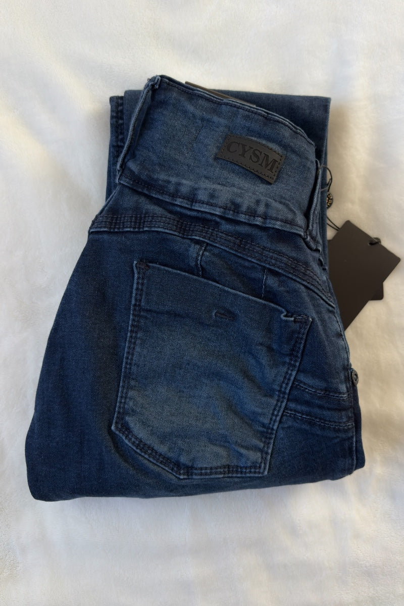 Folded blue jeans with a brand label on a light background