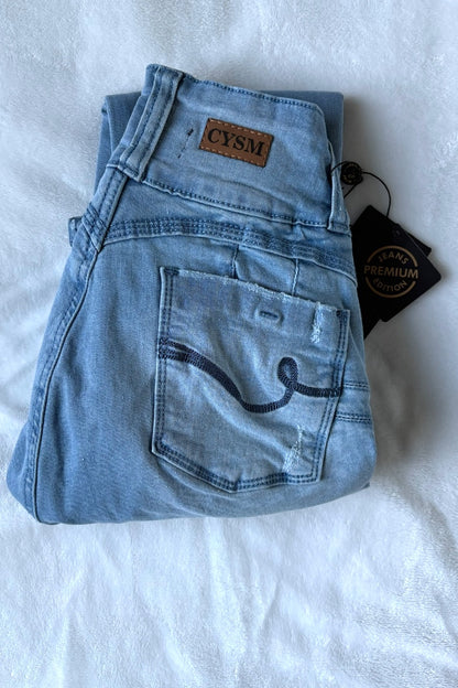 Folded light blue jeans with a brand tag on a white background