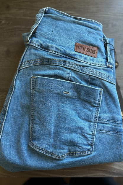 Folded blue jeans with a visible brand label on a wooden surface