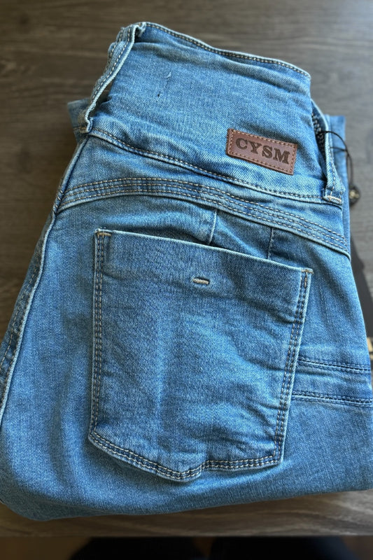 Folded blue jeans with a visible brand label on a wooden surface