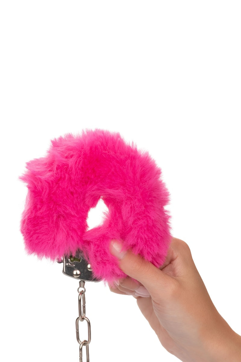 Hand holding a pink handcuff with a chain on a white background