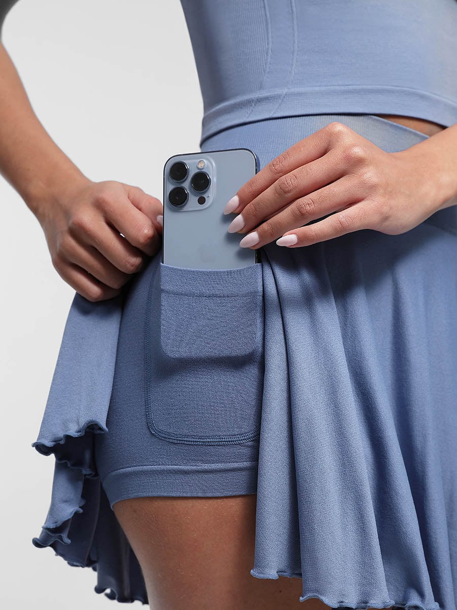 Person wearing a blue skirt holding a phone with a clear case.