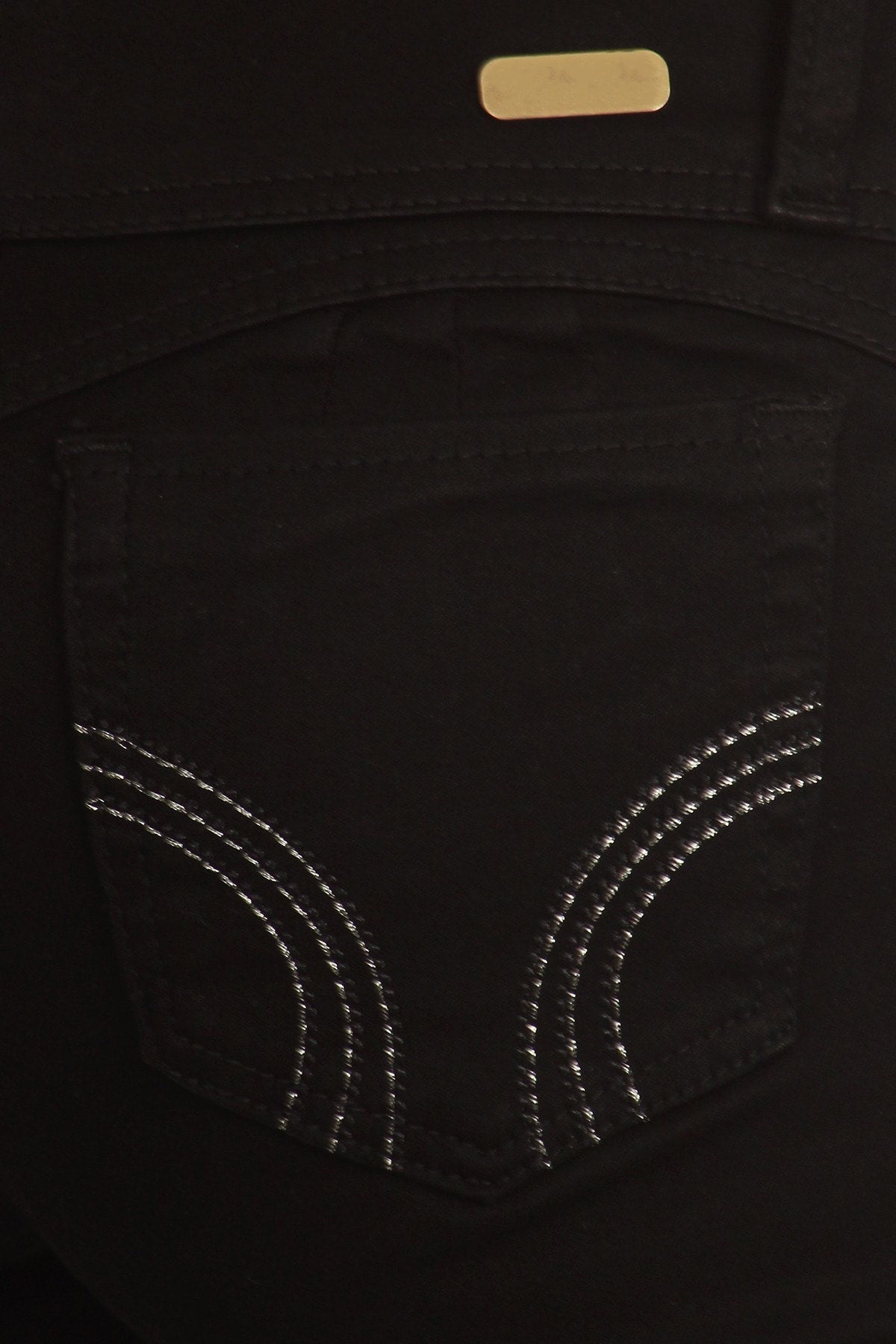 Close-up of a black pocket with silver stitching on a dark background