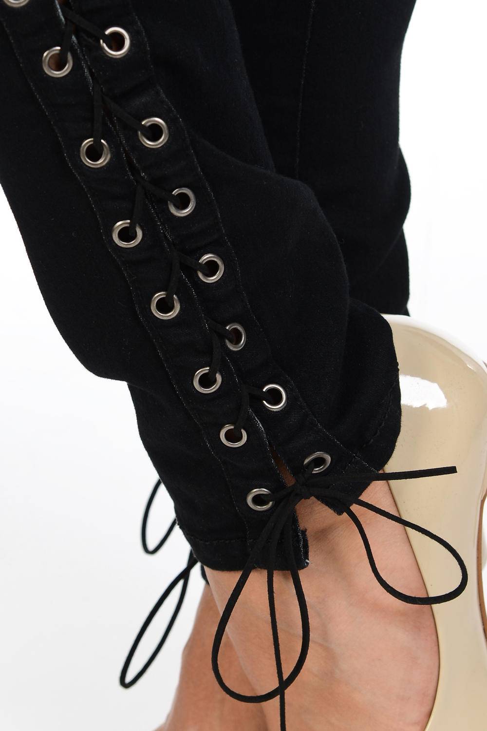 Black lace-up jeans with silver grommets on a white background