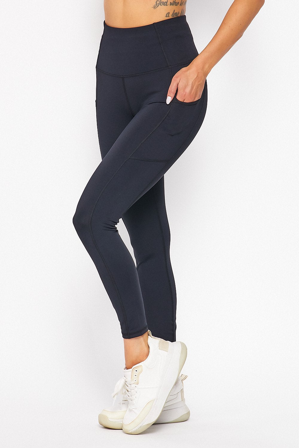 Person wearing black leggings and white sneakers on a white background