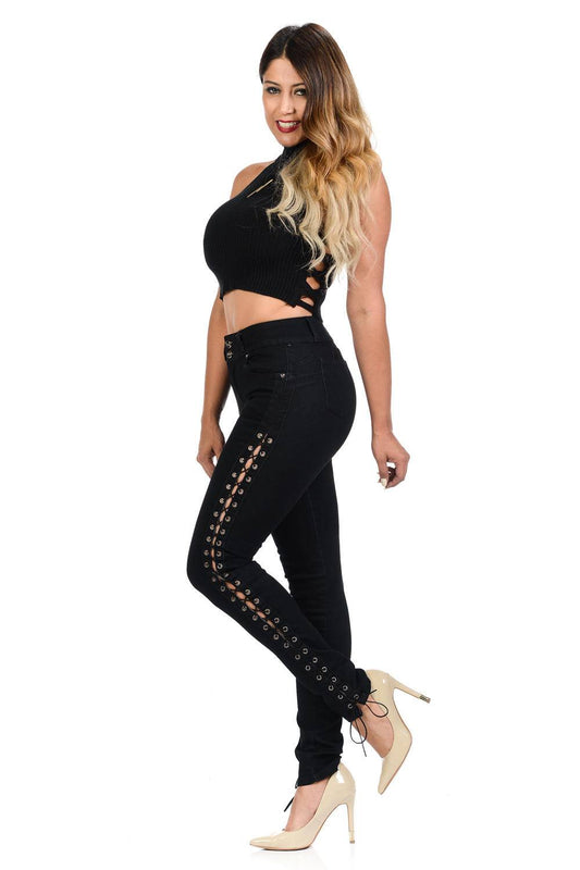 Woman wearing a black outfit with lace-up details on a white background