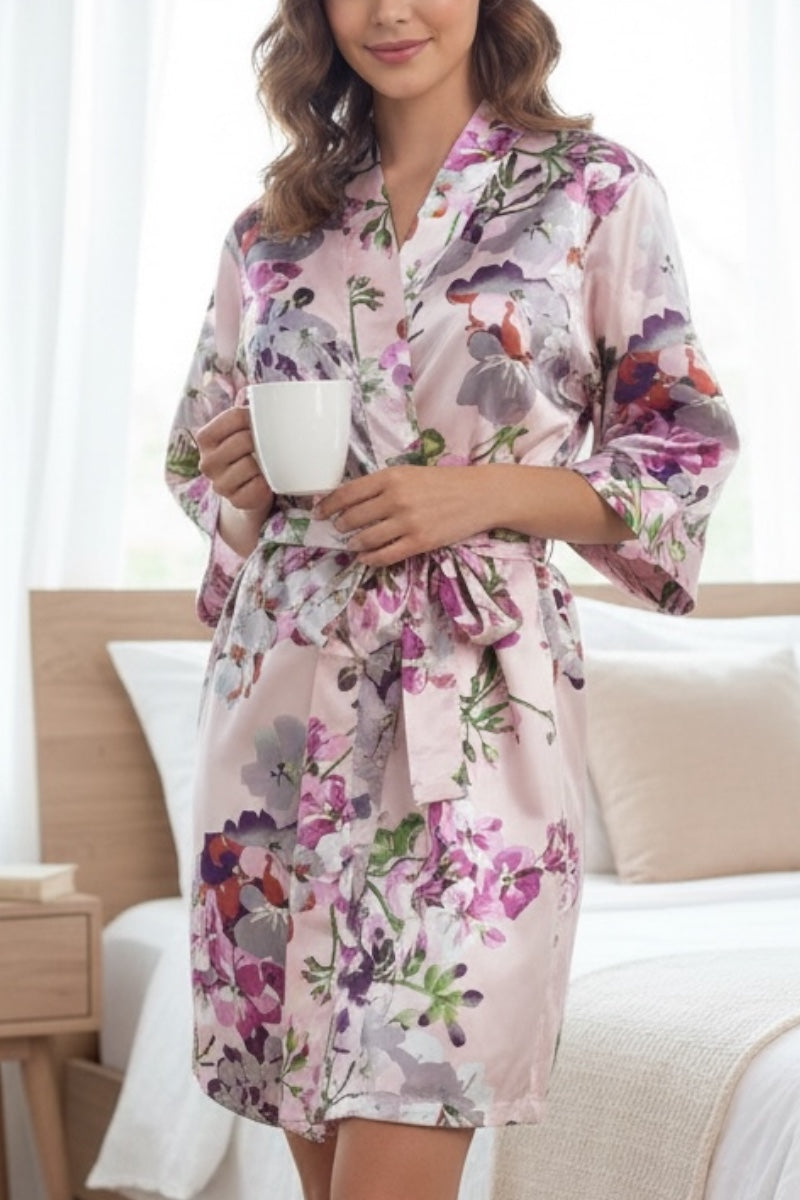 Woman wearing a pink floral robe holding a cup in a cozy room.