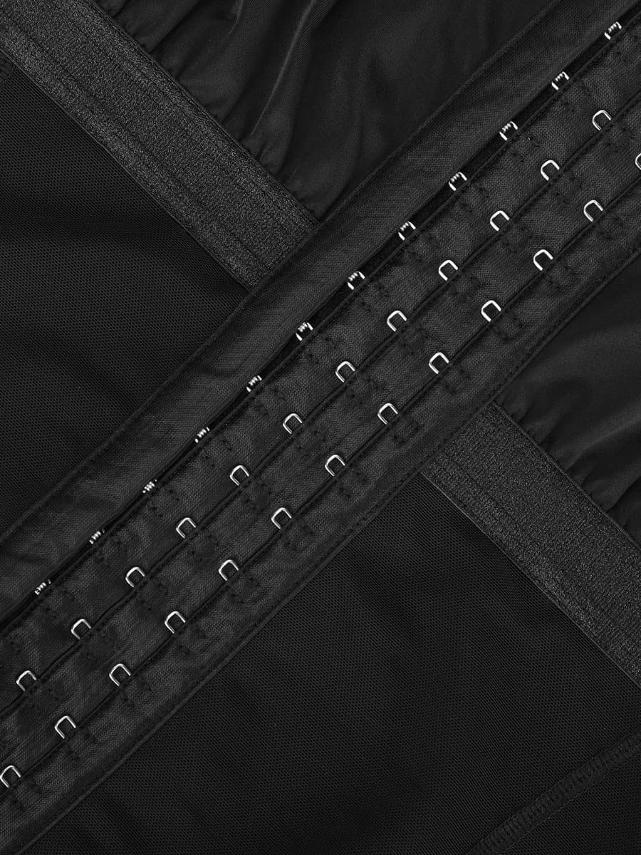 Close-up of a black garment with metal buttons and straps.